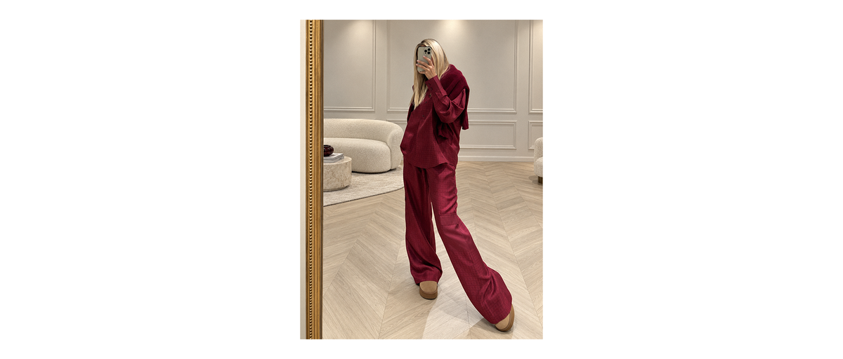 Emma Lederer, directrice artistique de la Maison MAX&MOI, photographiée dans notre showroom parisien, portant un pantalon cago en soie bordeaux, avec la chemise en soie assortie et un pull coordonné noué aux épaules. Un total look bordeaux au chic effortless. 