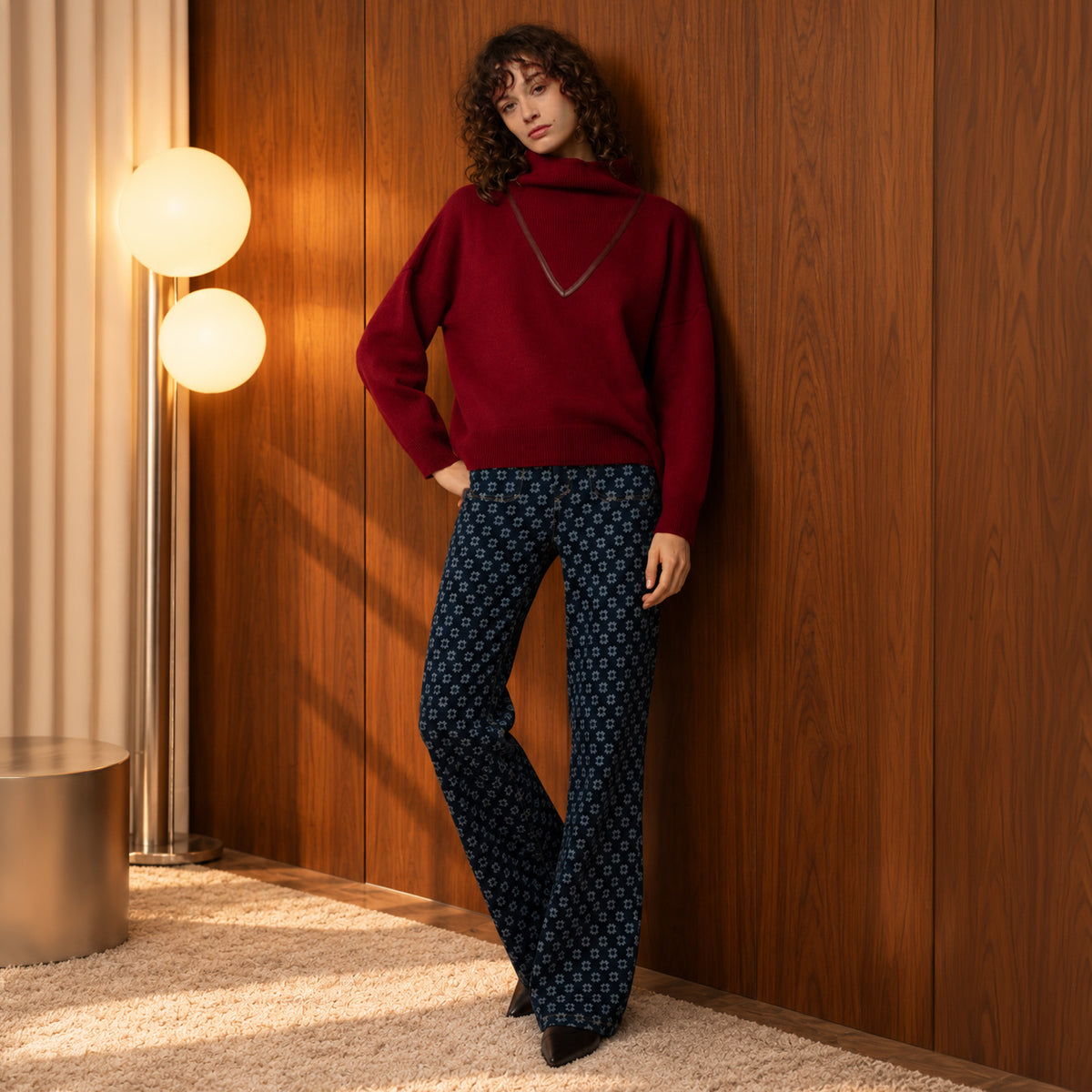 Pull à col roulé en maille bordeaux MAX&MOI avec détails en cuir, porté avec le jean flare bleu foncé à monogramme MAX&MOI. Une silhouette casual chic.