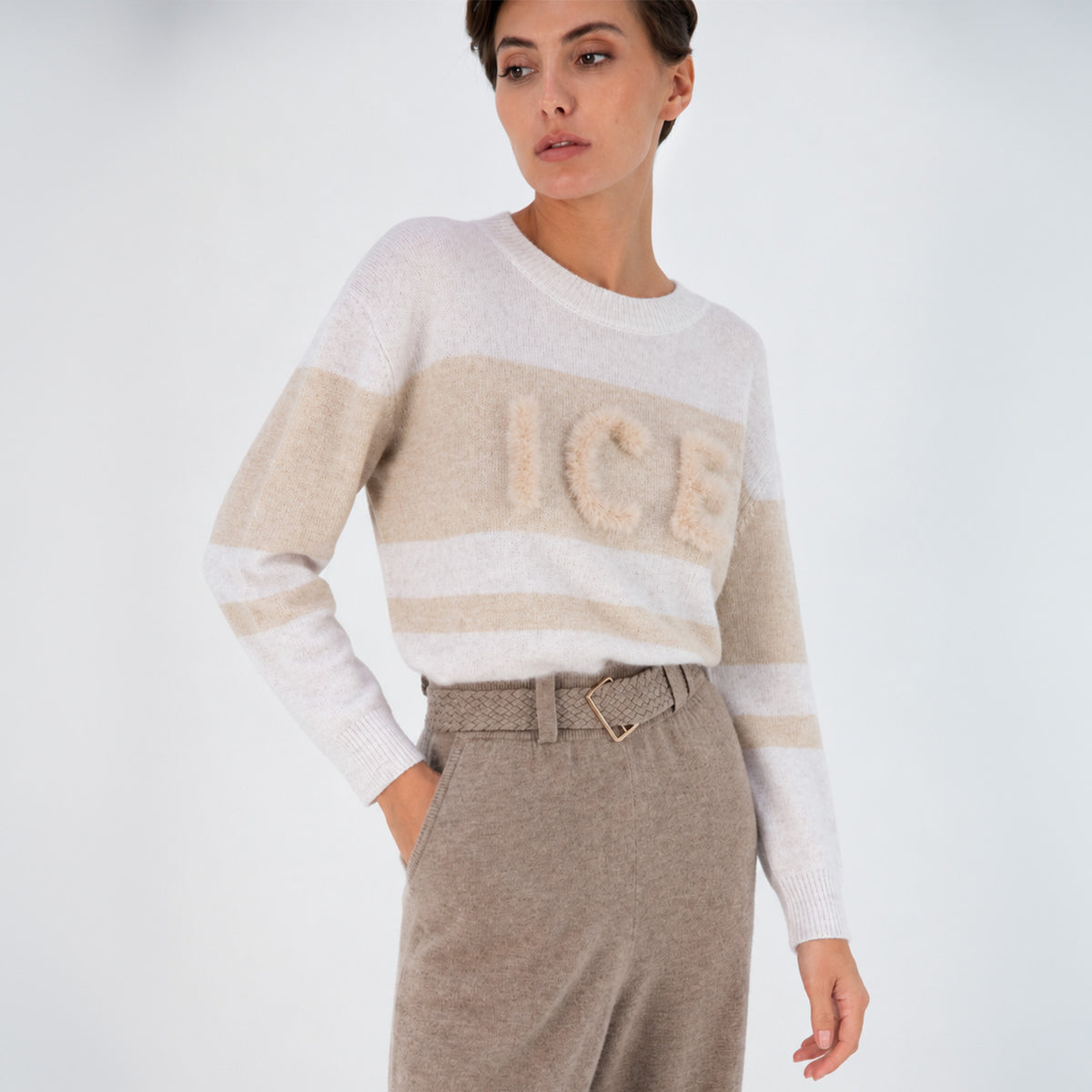 Pull PROUST rayé blanc et beige avec inscription ICE en vison, proposé en précommande. Le pull est porté avec le pantalon BLIZZARD Moka de la collection MAX&MOI Automne-Hiver 26. 